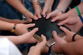 Hands joined in prayer around a Bible